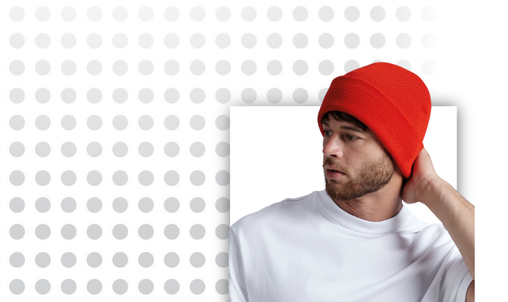 Young adult models a BC045 Beanie in red against a spotted background